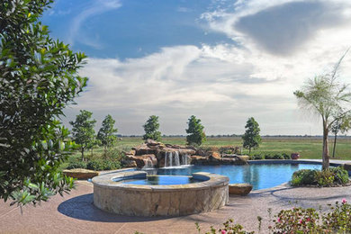 Design ideas for a large country backyard custom-shaped natural pool in Houston with a water feature and natural stone pavers.