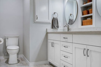 This is an example of a mid-sized transitional master bathroom in Dallas with shaker cabinets, white cabinets, a freestanding tub, an alcove shower, a two-piece toilet, grey walls, light hardwood floors, an undermount sink, beige floor and a hinged shower door.