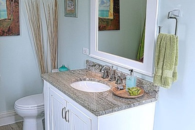 Mid-sized transitional beige tile light wood floor powder room photo in Chicago with shaker cabinets, white cabinets, a two-piece toilet, blue walls, an undermount sink and granite countertops