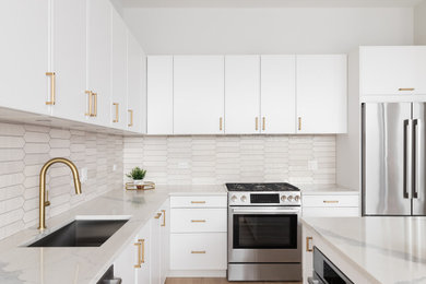 Eat-in kitchen - mid-sized contemporary medium tone wood floor and brown floor eat-in kitchen idea in Los Angeles with shaker cabinets, white cabinets, quartz countertops, white backsplash, ceramic backsplash, stainless steel appliances, an island, white countertops and an undermount sink