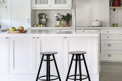 Imagen de cocinas en U romántico de tamaño medio abierto con fregadero bajoencimera, armarios estilo shaker, puertas de armario blancas, encimera de cuarzo compacto, salpicadero blanco, salpicadero de azulejos tipo metro, electrodomésticos blancos, suelo de cemento, península, suelo gris y encimeras blancas