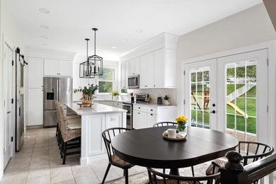 Mid-sized transitional u-shaped ceramic tile and beige floor eat-in kitchen photo in St Louis with a drop-in sink, recessed-panel cabinets, white cabinets, quartzite countertops, white backsplash, ceramic backsplash, stainless steel appliances, an island and white countertops