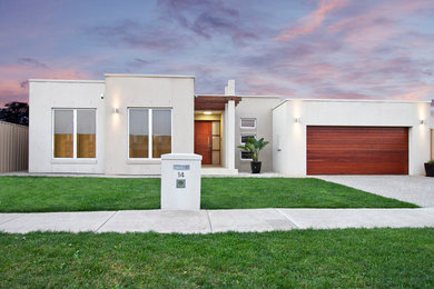 Mid-sized modern stucco house exterior in Melbourne with a flat roof and a metal roof.