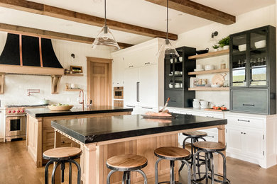 Inspiration for an expansive classic u-shaped kitchen in San Francisco with a belfast sink, recessed-panel cabinets, medium wood cabinets, engineered stone countertops, white splashback, engineered quartz splashback, integrated appliances, medium hardwood flooring, multiple islands, brown floors, white worktops and exposed beams.
