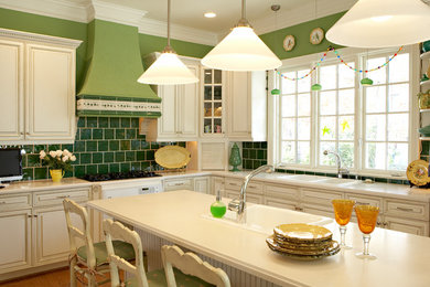 Inspiration for a mid-sized eclectic l-shaped medium tone wood floor and brown floor enclosed kitchen remodel in Other with a drop-in sink, raised-panel cabinets, white cabinets, solid surface countertops, green backsplash, ceramic backsplash and an island