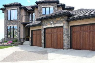 Example of a large arts and crafts attached three-car garage design in Calgary