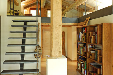 Modelo de salón tipo loft rural grande con suelo de madera clara, suelo marrón, madera y vigas vistas
