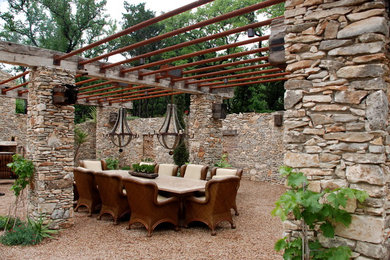 Example of a tuscan gravel patio design in Austin with a pergola