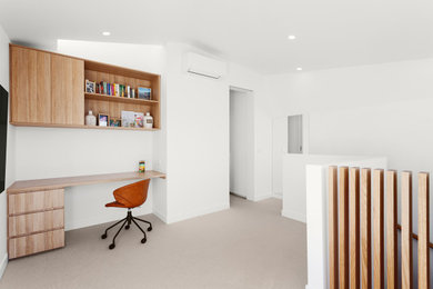 メルボルンにある高級な中くらいなコンテンポラリースタイルのおしゃれなホームオフィス・書斎 (白い壁、カーペット敷き、造り付け机) の写真