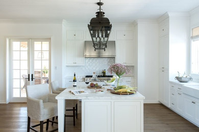 Inspiration for a contemporary eat-in kitchen in Austin with a farmhouse sink, white cabinets, marble benchtops, white splashback, stainless steel appliances, light hardwood floors and with island.