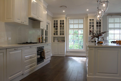 Ejemplo de cocina tradicional con puertas de armario blancas, salpicadero blanco, salpicadero de losas de piedra, electrodomésticos de acero inoxidable y una isla