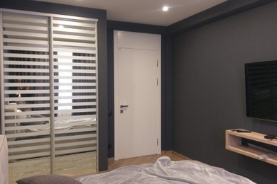 Стильный дизайн: хозяйская спальня среднего размера в современном стиле с черными стенами, полом из ламината, коричневым полом, обоями на стенах и акцентной стеной без камина - последний тренд
