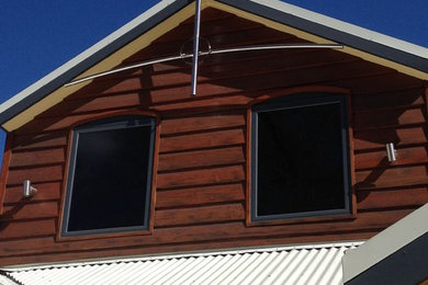 Large traditional two-storey yellow house exterior in Perth with wood siding, a gable roof and a metal roof.