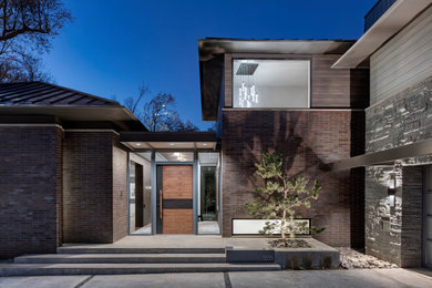 Example of a mid-sized minimalist brown two-story brick house exterior design in Dallas with a hip roof, a metal roof and a gray roof