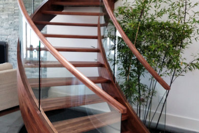Large trendy wooden curved open staircase photo in Charleston