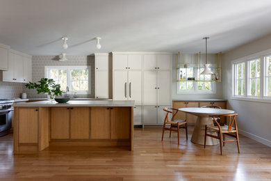 Inspiration for a mid-sized transitional l-shaped light wood floor eat-in kitchen remodel in Los Angeles with an undermount sink, raised-panel cabinets, medium tone wood cabinets, quartz countertops, gray backsplash, ceramic backsplash, paneled appliances, an island and gray countertops