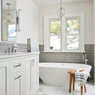 Immagine di una grande stanza da bagno padronale tradizionale con ante a filo, ante grigie, vasca freestanding, doccia ad angolo, piastrelle grigie, piastrelle diamantate, pareti bianche, pavimento in gres porcellanato, lavabo sottopiano, top in quarzo composito, pavimento bianco, porta doccia a battente, top grigio, due lavabi, mobile bagno incassato e boiserie