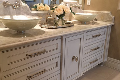 Inspiration for a large transitional master beige tile and stone tile limestone floor corner shower remodel in New York with furniture-like cabinets, white cabinets, an undermount tub, a two-piece toilet, gray walls, a vessel sink and quartzite countertops