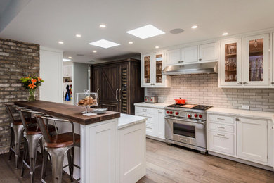 Large transitional open plan kitchen in San Francisco with a farmhouse sink, shaker cabinets, white cabinets, blue splashback, panelled appliances, dark hardwood floors and a peninsula.