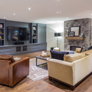 Réalisation d'une grande salle de cinéma tradition ouverte avec un mur gris, un sol en bois foncé et un téléviseur encastré.