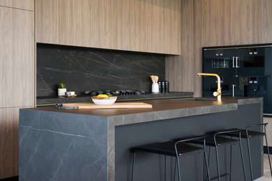 Example of a mid-sized minimalist single-wall porcelain tile and gray floor eat-in kitchen design in Montreal with an undermount sink, flat-panel cabinets, light wood cabinets, gray backsplash, black appliances and an island