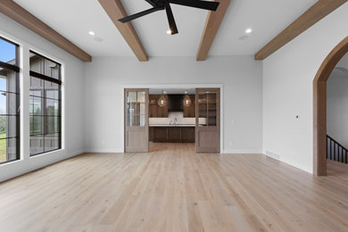 Inspiration for a large timeless enclosed medium tone wood floor, brown floor and exposed beam living room remodel in Other with white walls, a standard fireplace, a stone fireplace and a wall-mounted tv