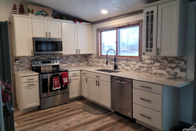 Inspiration for a small modern l-shaped vinyl floor and vaulted ceiling eat-in kitchen remodel in Other with an undermount sink, white cabinets, quartz countertops, mosaic tile backsplash, stainless steel appliances and white countertops