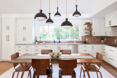 Example of a mid-century modern l-shaped medium tone wood floor and brown floor eat-in kitchen design in Raleigh with white cabinets, porcelain backsplash, stainless steel appliances, an undermount sink, flat-panel cabinets, red backsplash, no island and gray countertops