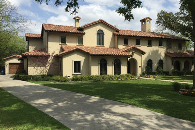 Inspiration for a large mediterranean beige two-story exterior home remodel in Dallas with a tile roof and a brown roof