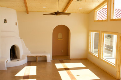 アルバカーキにある広いトランジショナルスタイルのおしゃれなLDK (コンクリートの床、コーナー設置型暖炉、茶色い床、三角天井) の写真