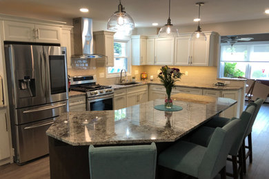 Inspiration for a transitional laminate floor and gray floor kitchen remodel in Grand Rapids with an undermount sink, recessed-panel cabinets, medium tone wood cabinets, granite countertops, white backsplash, ceramic backsplash, stainless steel appliances and an island