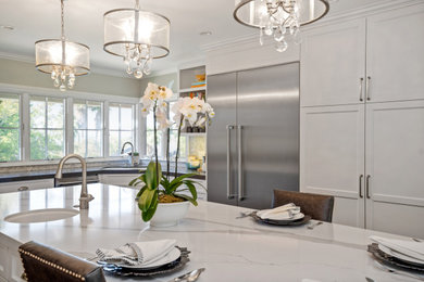 Example of a mid-sized transitional u-shaped dark wood floor kitchen design in Los Angeles with recessed-panel cabinets, white cabinets, quartz countertops, white backsplash, marble backsplash, stainless steel appliances and an island