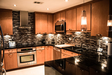 Inspiration for a large modern u-shaped marble floor enclosed kitchen remodel in Miami with a double-bowl sink, flat-panel cabinets, medium tone wood cabinets, solid surface countertops, multicolored backsplash, matchstick tile backsplash, stainless steel appliances and no island