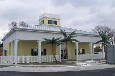 Foto de fachada de casa amarilla clásica de tamaño medio de dos plantas con revestimiento de madera, tejado a cuatro aguas y tejado de metal