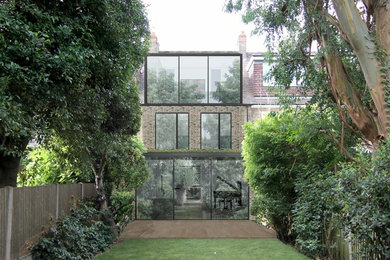 Photo of a large and brown contemporary brick terraced house in London with three floors, a flat roof and a green roof.