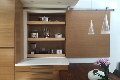 Inspiration for a modern light wood floor eat-in kitchen remodel in San Diego with an undermount sink, flat-panel cabinets, light wood cabinets, quartz countertops, white backsplash, glass sheet backsplash, stainless steel appliances and an island