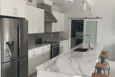 Mid-sized contemporary galley open plan kitchen in New York with an undermount sink, shaker cabinets, white cabinets, quartzite benchtops, grey splashback, mosaic tile splashback, stainless steel appliances, porcelain floors, with island and white floor.