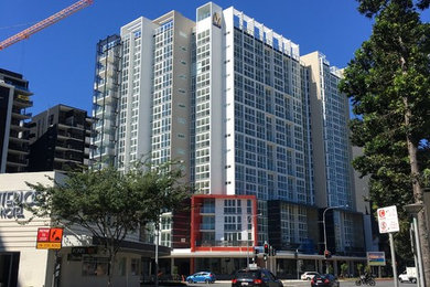 Photo of a contemporary three-storey concrete apartment exterior in Brisbane.