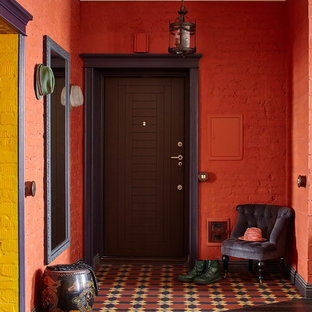 Réalisation d'un hall d'entrée bohème de taille moyenne avec un mur rouge, un sol en carrelage de céramique, une porte simple, une porte en bois foncé et un sol multicolore.