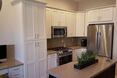 Inspiration for a mid-sized transitional l-shaped medium tone wood floor open concept kitchen remodel in Phoenix with white cabinets, quartzite countertops, beige backsplash, stainless steel appliances and an island