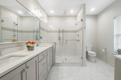 Photo of a mid-sized beach style master bathroom in Milwaukee with beige cabinets, ceramic floors, an undermount sink, engineered quartz benchtops, grey floor, a hinged shower door, white benchtops and a double vanity.