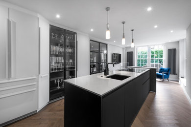 This is an example of a modern enclosed kitchen in London with black cabinets and an island.