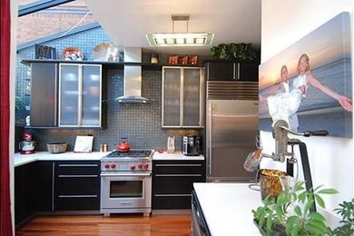 Example of a small trendy l-shaped dark wood floor enclosed kitchen design in Other with an undermount sink, flat-panel cabinets, black cabinets, quartz countertops, green backsplash, glass tile backsplash, stainless steel appliances and no island