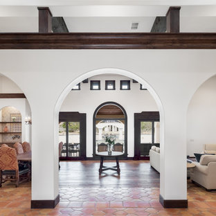 Ejemplo de salón con barra de bar abierto, mediterráneo, grande, sin televisor, con paredes blancas, suelo de baldosas de terracota, chimenea tradicional, marco de chimenea de baldosas y/o azulejos y suelo marrón