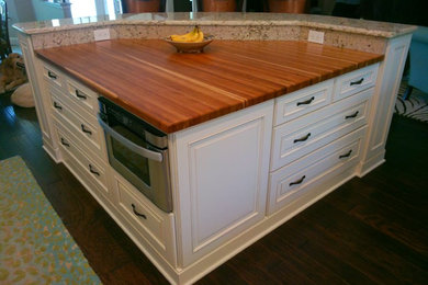Example of a large classic u-shaped light wood floor eat-in kitchen design in Tampa with a drop-in sink, flat-panel cabinets, granite countertops, beige backsplash, ceramic backsplash, stainless steel appliances, an island and white cabinets