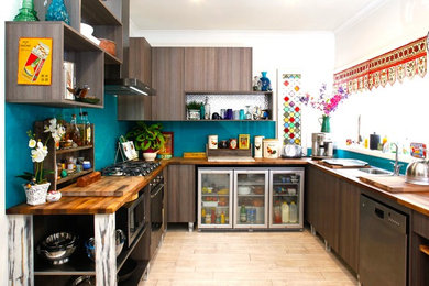 This is an example of a mid-sized beach style u-shaped kitchen pantry in Perth with a drop-in sink, flat-panel cabinets, dark wood cabinets, wood benchtops, blue splashback, glass sheet splashback, stainless steel appliances, light hardwood floors and no island.