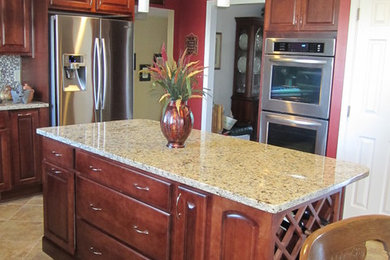 Eat-in kitchen - large traditional ceramic tile eat-in kitchen idea in DC Metro with raised-panel cabinets, medium tone wood cabinets, granite countertops, multicolored backsplash, mosaic tile backsplash, stainless steel appliances and an island