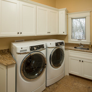 Photo of a medium sized contemporary galley utility room in Chicago with a submerged sink, shaker cabinets, white cabinets, granite worktops, limestone flooring, a side by side washer and dryer, beige floors and orange walls.