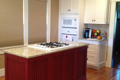 Inspiration for a small farmhouse u-shaped medium tone wood floor enclosed kitchen remodel in Other with a farmhouse sink, louvered cabinets, red cabinets, granite countertops, beige backsplash, subway tile backsplash, white appliances and an island