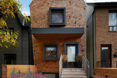 This is an example of a mid-sized contemporary two-storey house exterior with wood siding, a gable roof and a metal roof.